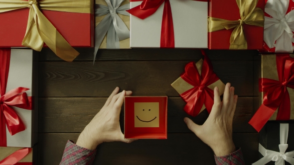 Top Down Shot of Adult Man Opening Christmas Present Box with Sticky Note with Smile Inside