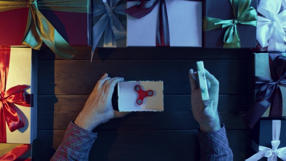 Adult Man Unpacking New Year Gift Box with Fidget Spinner Inside, Top Down Shot