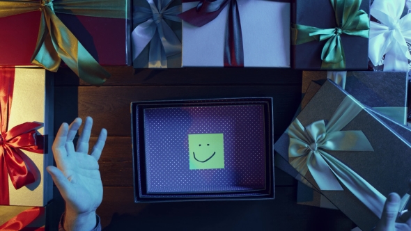 Top Down Shot of Adult Man Opening New Year Present with Only a Sticky Note with Smile Inside