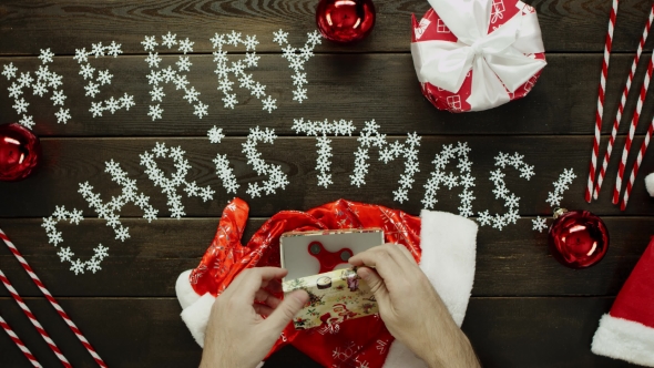 Santa Claus Plays with Fidget Spinner and Puts It in Gift Box on New Year Table, Top Down Shot