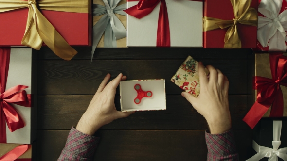 Adult Man Unpacking Christmas Gift Box with Fidget Spinner Inside, Top Down Shot