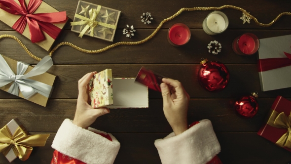 Top Down Shot of Man in Santa Claus Suit Putting Bank Card in Christmas Gift Box By Decorated