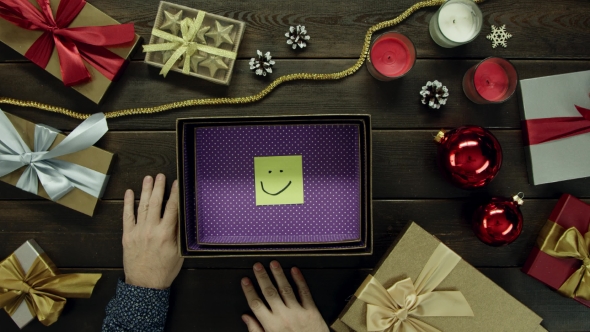 Top Down Shot of Adult Man Unboxing New Year Present Box with Sticky Note with Smile Inside