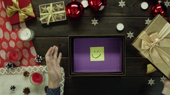 Top Down Shot of Man Opening Xmas Present Box with Just a Sticky Note with Smile Inside