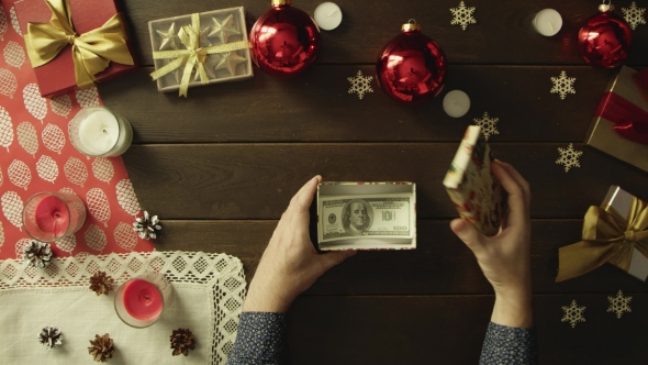 Adult Man Opens Christmas Present Box with Dollars Inside, Top Down Shot