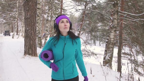 Girl Walks Through the Winter Forest with a Mat for Classes