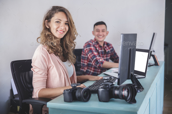 two photographers smiling while editing photos in their computer Stock Photo by odua