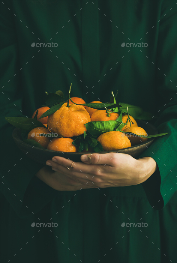 Fresh tangerine fruit with leaves in plate in female hands - Stock Photo - Images