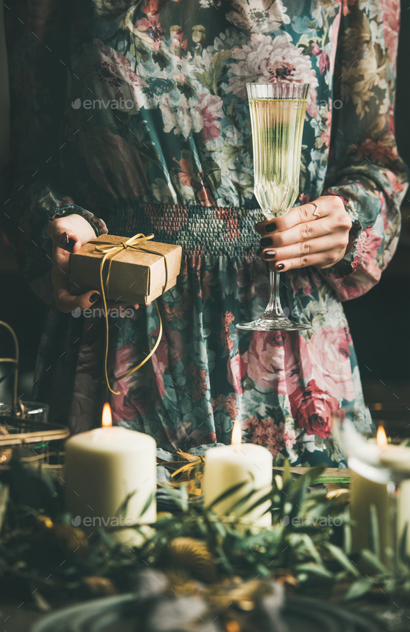 Woman holding glass of champaigne and gift box, Christmas eve - Stock Photo - Images