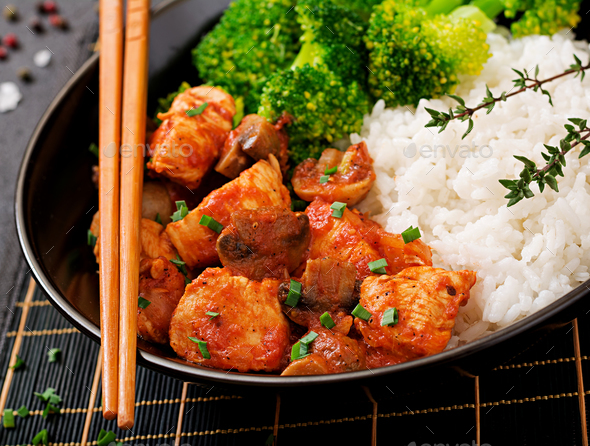 Pieces of chicken fillet with mushrooms stewed in tomato sauce with boiled broccoli Stock Photo by Timolina