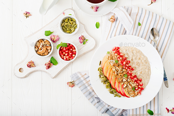 Tasty and healthy oatmeal porridge with apples, pomegranate and nuts. - Stock Photo - Images