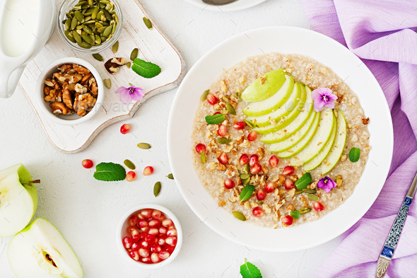 Tasty and healthy oatmeal porridge with apples, pomegranate and nuts. - Stock Photo - Images