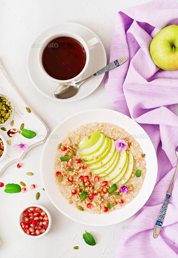 Tasty and healthy oatmeal porridge with apples, pomegranate and nuts - Stock Photo - Images