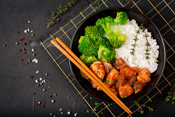 Pieces of chicken fillet with mushrooms stewed in tomato sauce with boiled broccoli and rice.