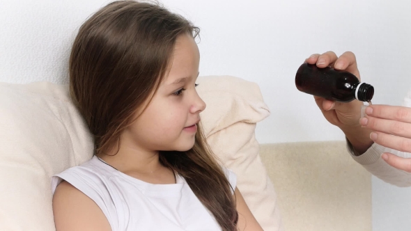 Mother or Doctor Giving Medicine Syrup To Her Sick Daughter in Bed