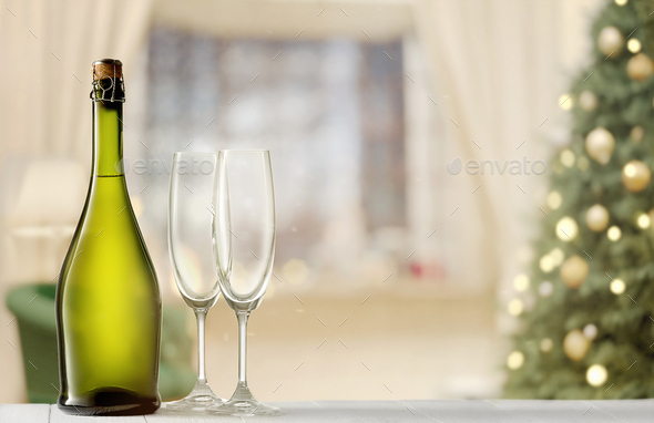 Glasses with champagne and bottle over sparkling holiday background