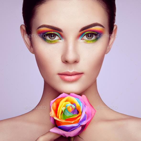 Portrait of beautiful young woman with rainbow rose - Stock Photo - Images