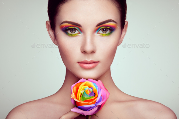 Portrait of beautiful young woman with rainbow rose - Stock Photo - Images