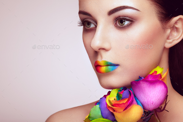 Portrait of beautiful young woman with rainbow rose - Stock Photo - Images