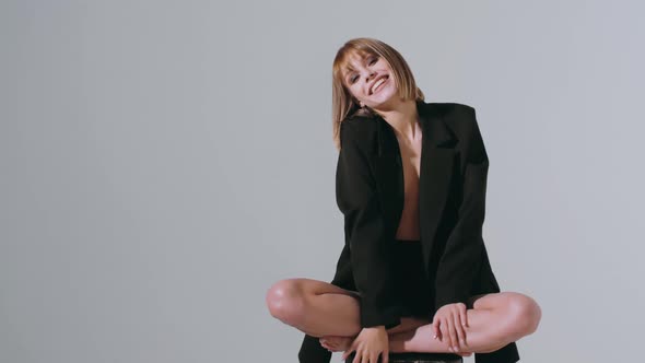 Young caucasian woman with bob hair in black suit jacket sitting in lotus position