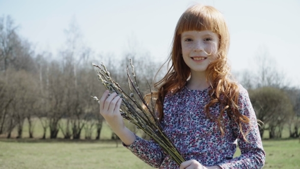 Happy Little Girl Holding a Spring Bunch of Branches in the Park