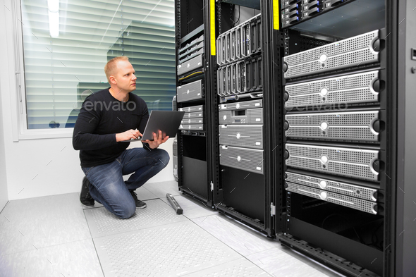 Consultant Using Laptop While Monitoring Servers In Datacenter Stock Photo by kjekol