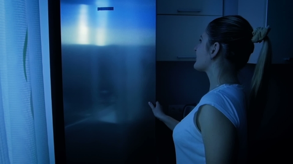 Woman Taking Fresh Apple From Refrigerator at Night. Concept of Healthy alt