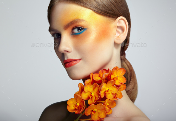 Portrait of beautiful young woman with orchid - Stock Photo - Images