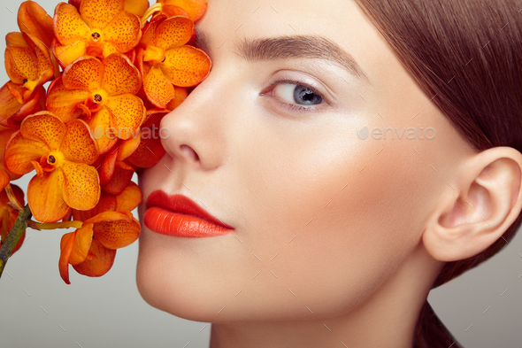 Portrait of beautiful young woman with orchid - Stock Photo - Images