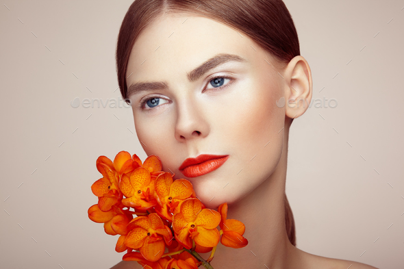Portrait of beautiful young woman with orchid - Stock Photo - Images