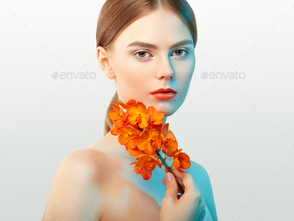 Portrait of beautiful young woman with orchid - Stock Photo - Images