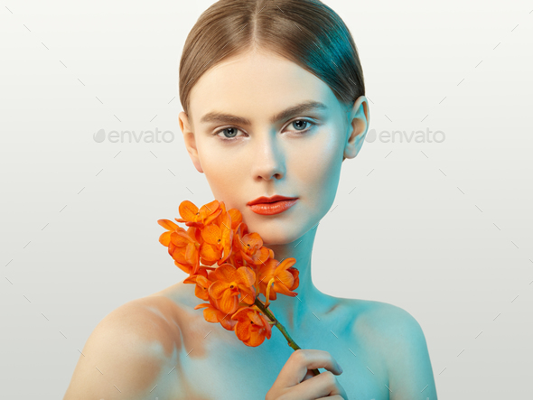 Portrait of beautiful young woman with orchid - Stock Photo - Images