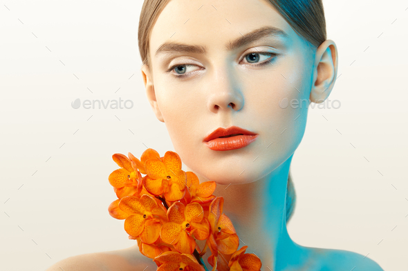 Portrait of beautiful young woman with orchid - Stock Photo - Images