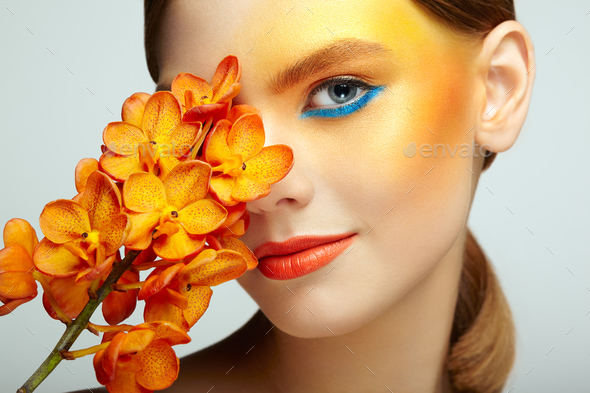 Portrait of beautiful young woman with orchid - Stock Photo - Images