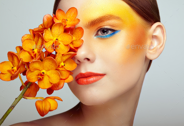 Portrait of beautiful young woman with orchid - Stock Photo - Images