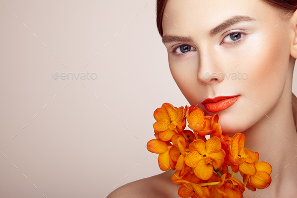 Portrait of beautiful young woman with orchid - Stock Photo - Images