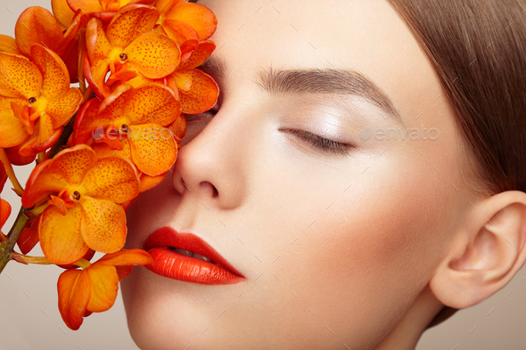 Portrait of beautiful young woman with orchid - Stock Photo - Images