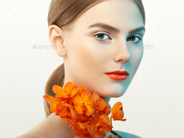 Portrait of beautiful young woman with orchid - Stock Photo - Images