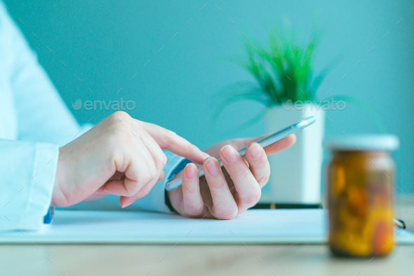 General practitioner using smartphone in office - Stock Photo - Images