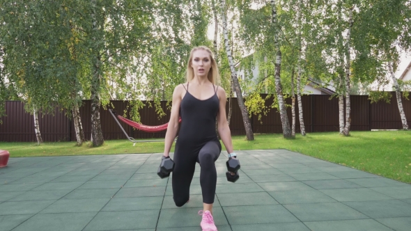 Muscular Fitness Woman Doing Walking Lunges with Dumbbells in Park