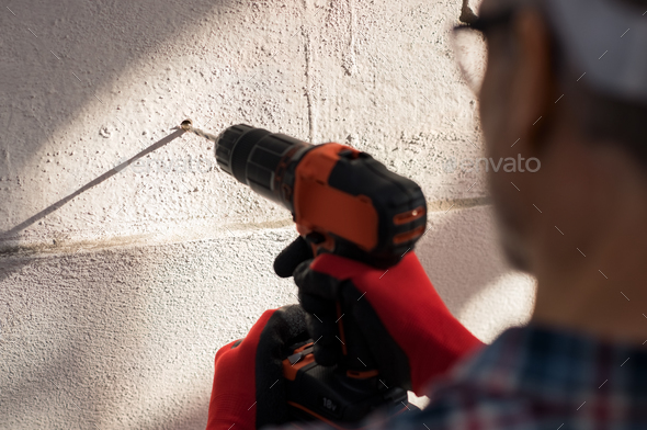 Man drilling hole in wall - Stock Photo - Images