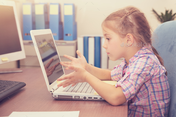Little girl doing homework on the laptop - Stock Photo - Images