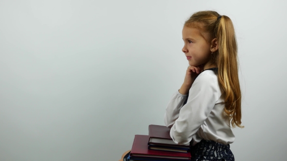 School Girl in Uniform Sits Elbows on Books and Smiling at Camera