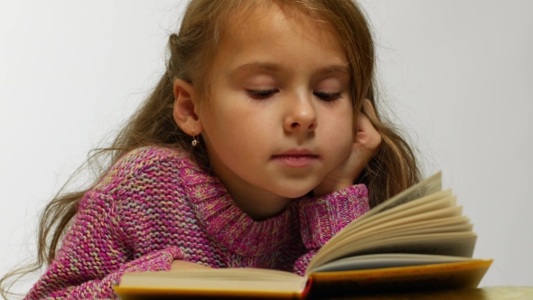 View of a Girl Reading a Book. A Young Cute Girl Reads a Book in a Whisper alt