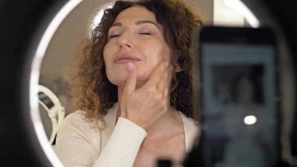 Positive Beautiful Middle Aged Woman Demonstrates the Application of a Moisturizing and Nourishing