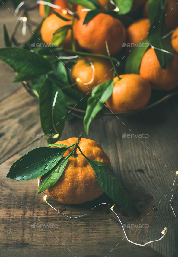 Fresh tangerines with leaves and light garland - Stock Photo - Images