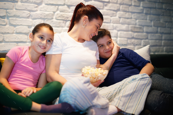 Single Mother And Children Watching TV At Night Stock Photo by diego_cervo