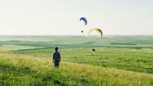 The Boy Is Standing in the Steppe Over Which Paragliders Hover