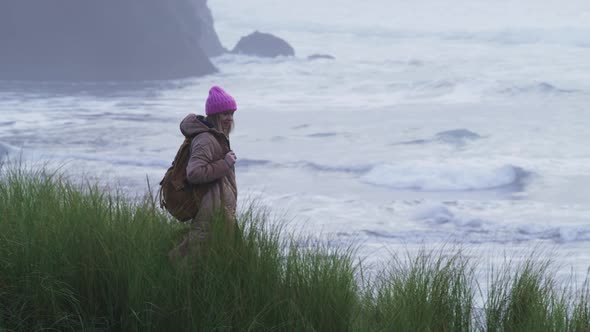 Slow Motion RED Camera Shot with Woman at Scenic Rocks in Stormy Ocean Shore 6K alt