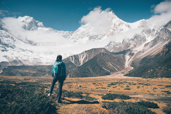 Woman with backpack looking on snow covered mountains - Stock Photo - Images